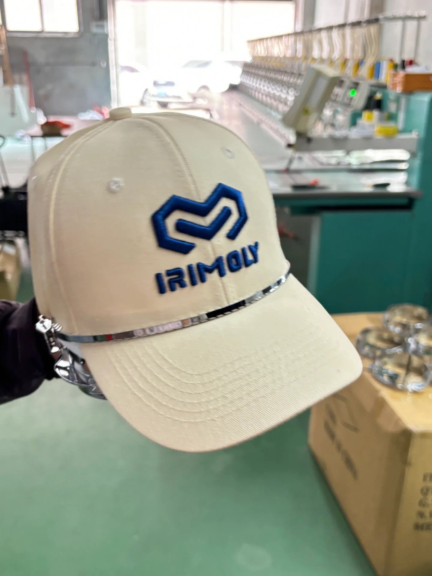 Finished 3D puff embroidered logo on a cream baseball cap secured in a cap embroidery frame.