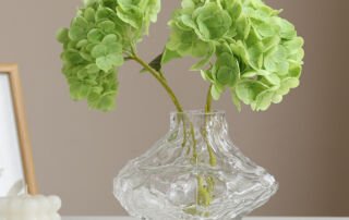 Green artificial hydrangea flowers in glass vase for decorative use