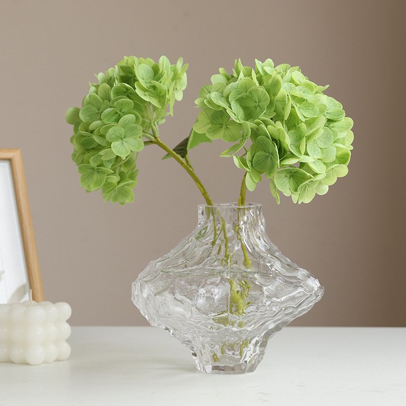 Green artificial hydrangea flowers in glass vase for decorative use