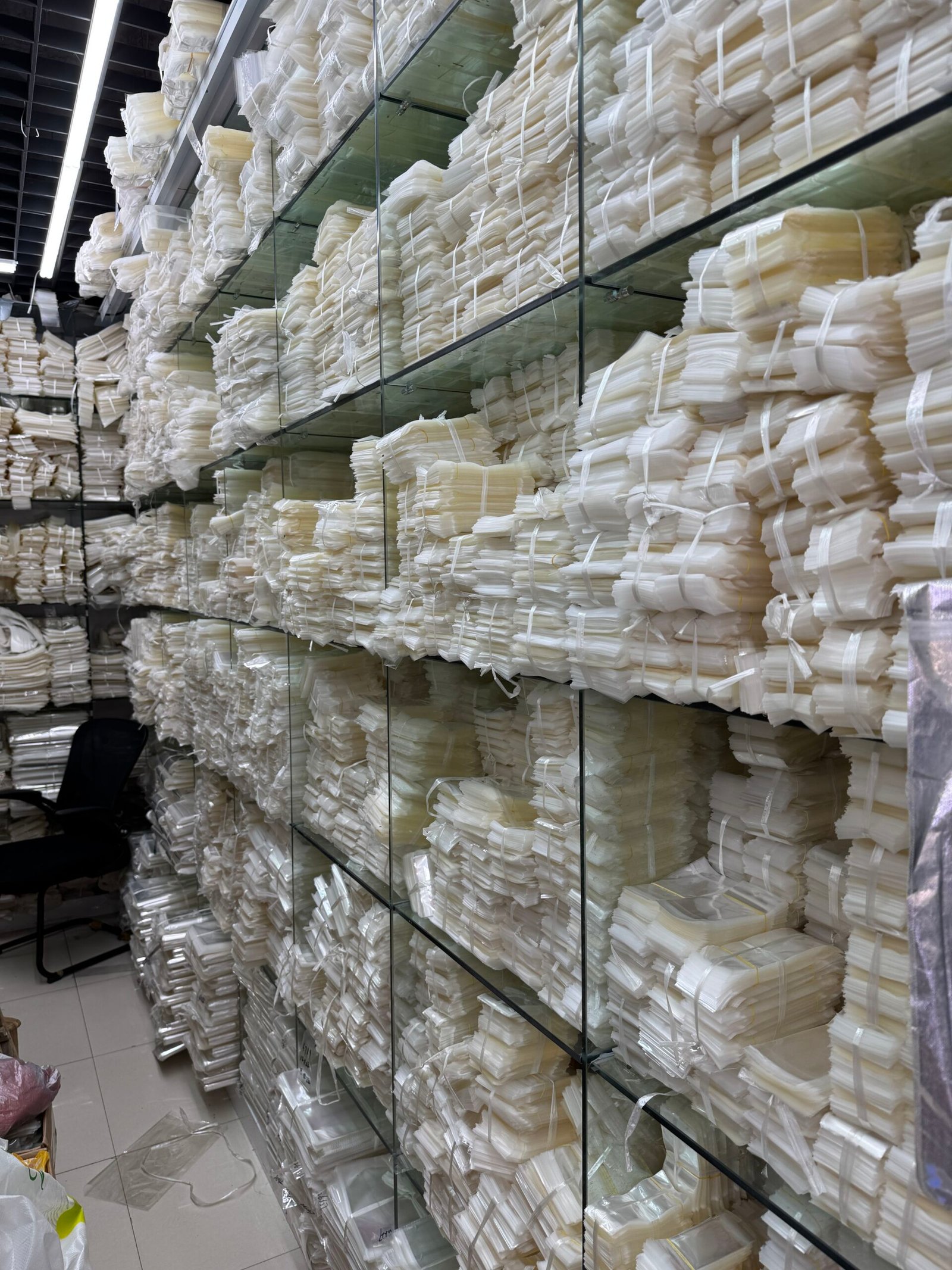 Shelves filled with bundled clear OPP bags in multiple sizes, ready stock at a Yiwu jewelry packaging supplier.