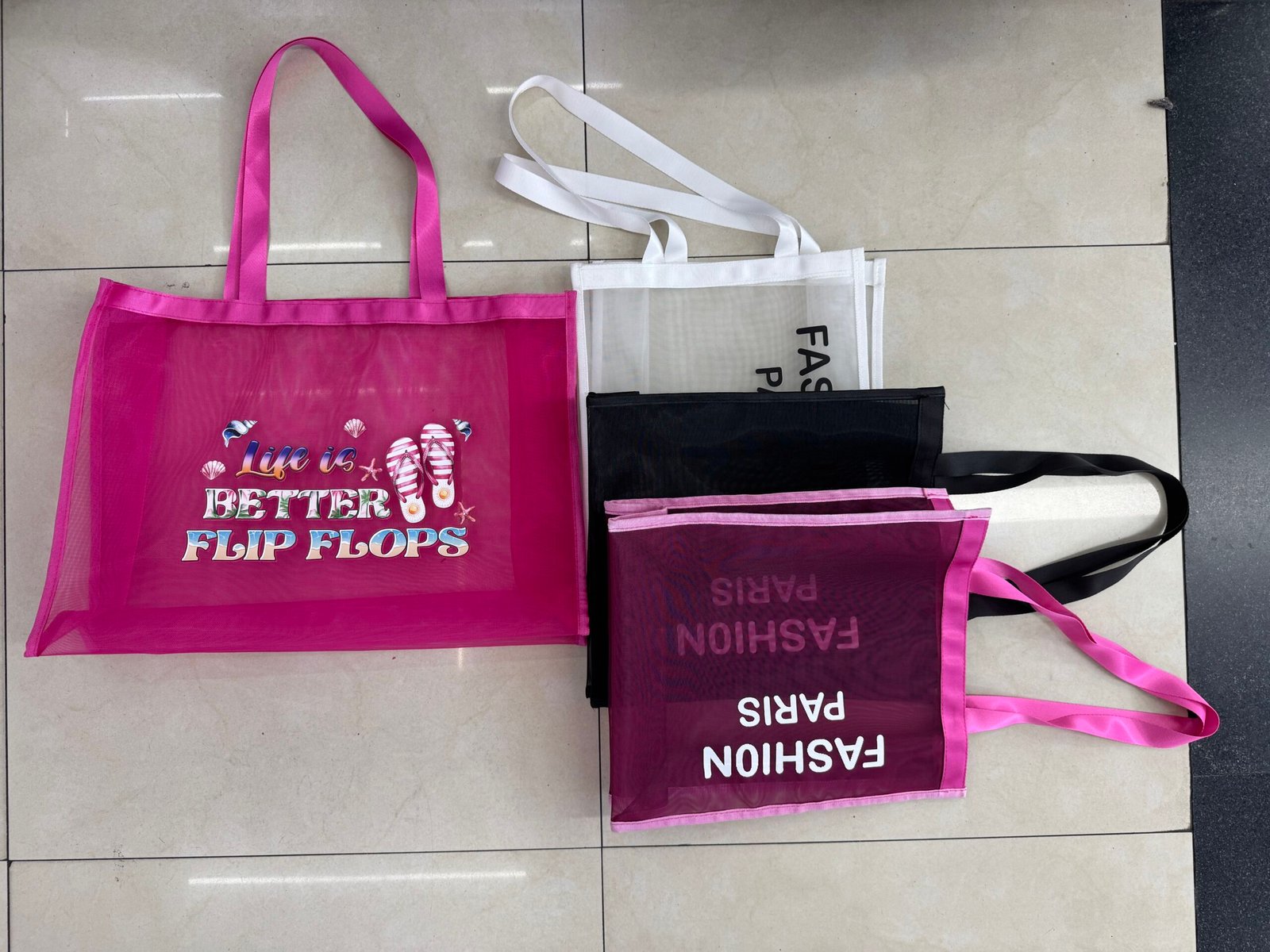 Custom nylon mesh shopping bags in pink white and black with webbing handles transparent mesh body and printed logos