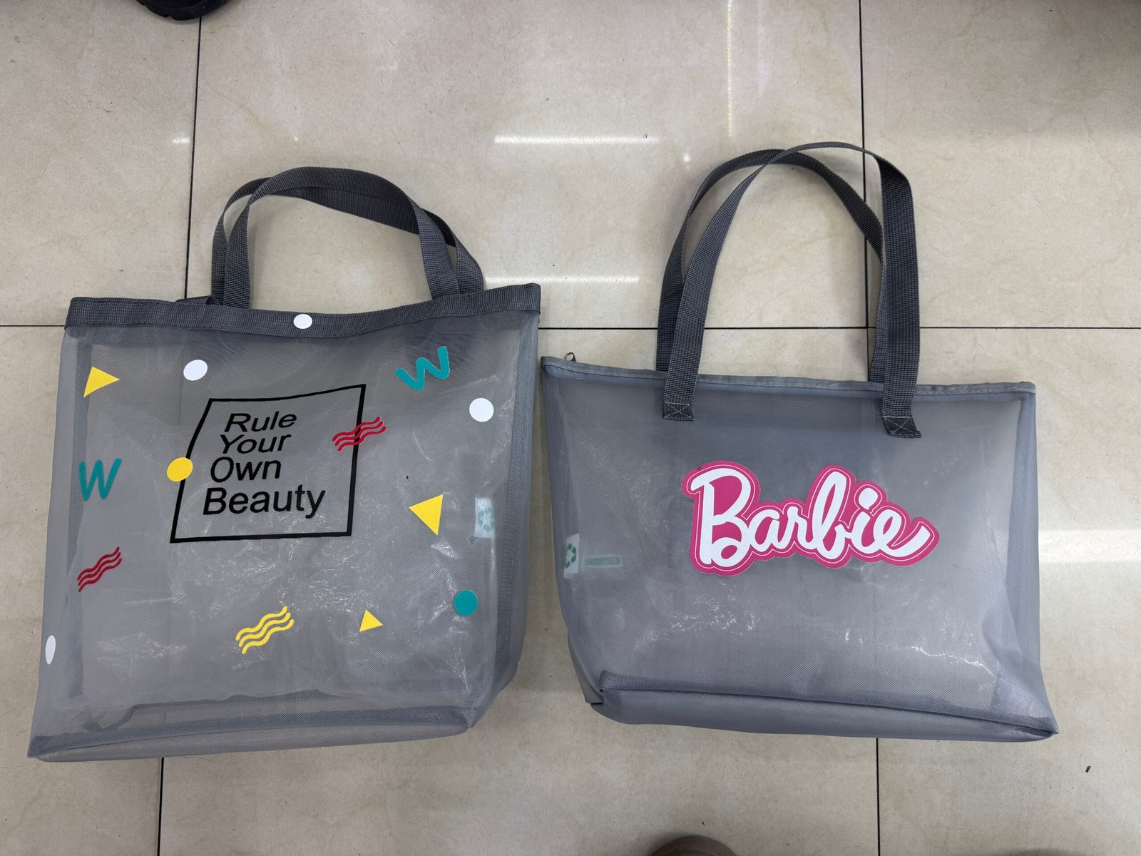 Two gray custom nylon mesh tote bags with different logo printing styles and reinforced handles