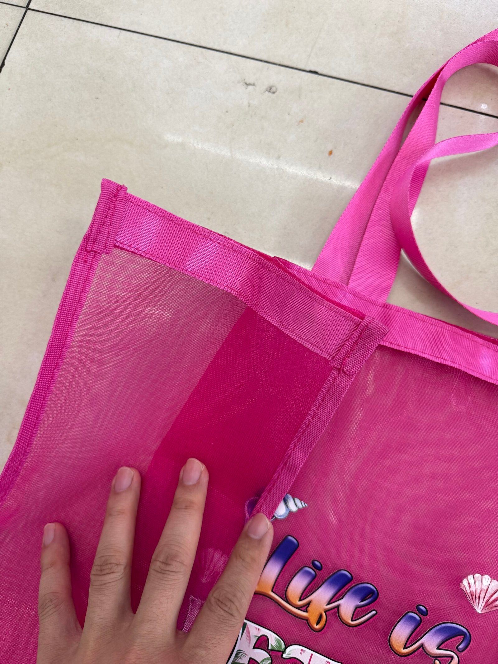 Pink nylon mesh shopping bag corner detail with reinforced stitching webbing handle and edge binding