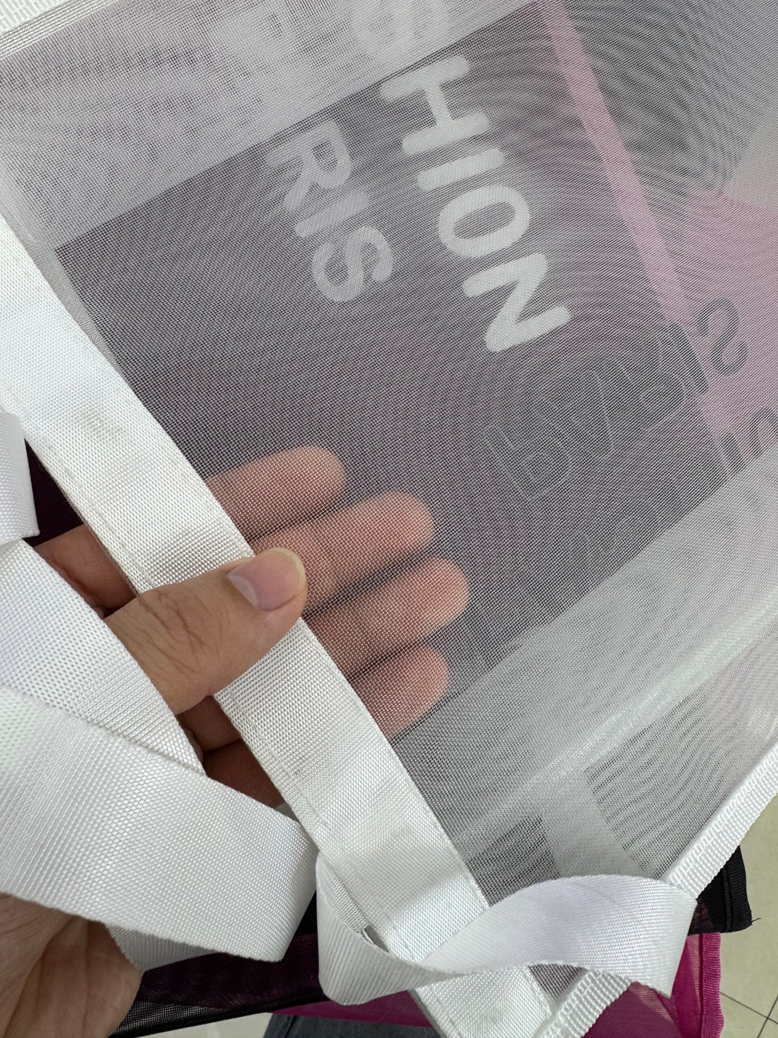 Close-up of white nylon mesh shopping bag fabric texture webbing handle and stitching
