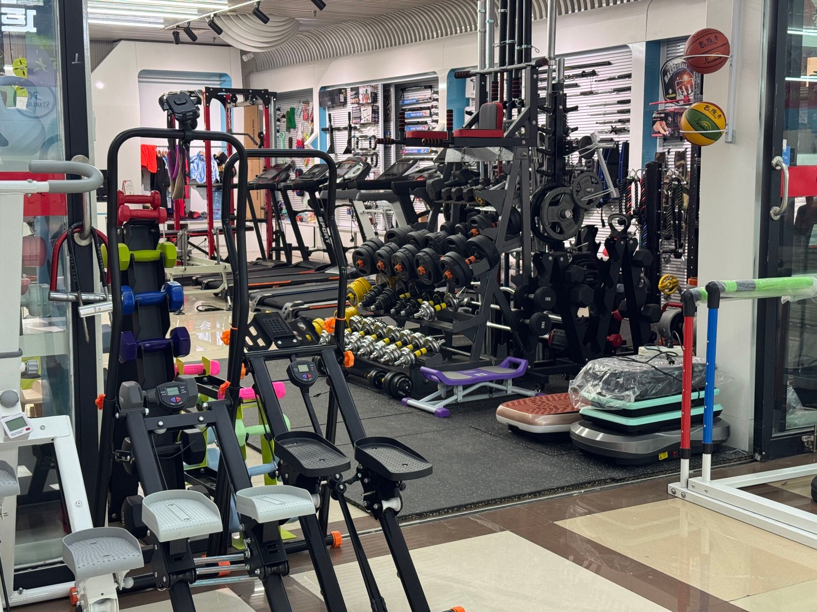 Gym equipment shop in Yiwu Sports Market with treadmills, dumbbells, and strength machines