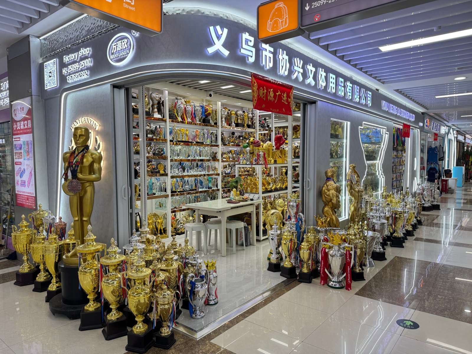Trophy and awards wholesale shop in Yiwu Sports Market with gold and silver cups on display