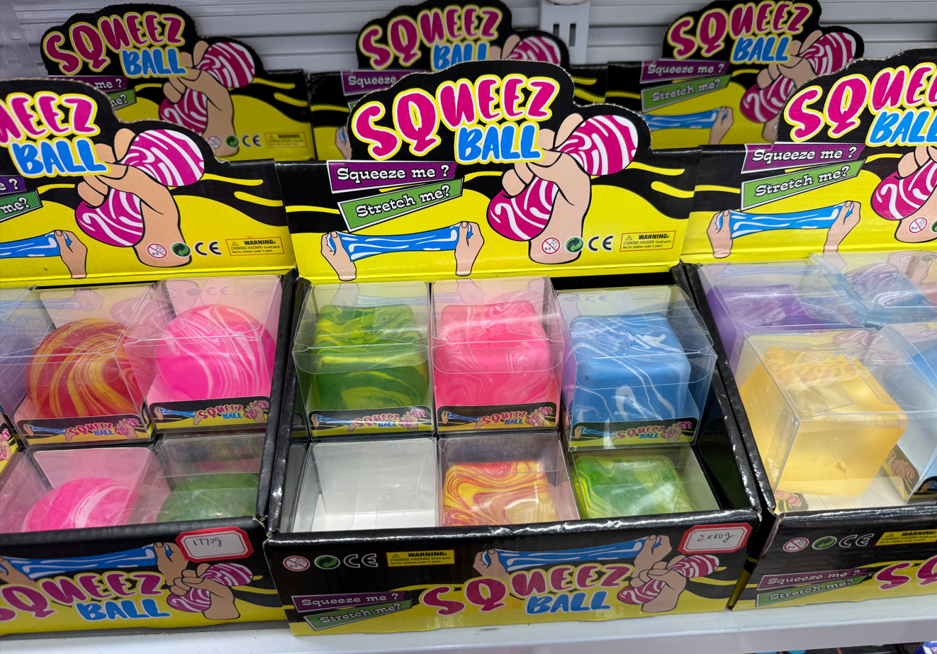 Assorted colorful squeeze ball stress relief toys in clear retail display boxes, including pink, green, blue, yellow, and purple fidget balls, photographed at Yiwu Toy Market for wholesale toy buyers.