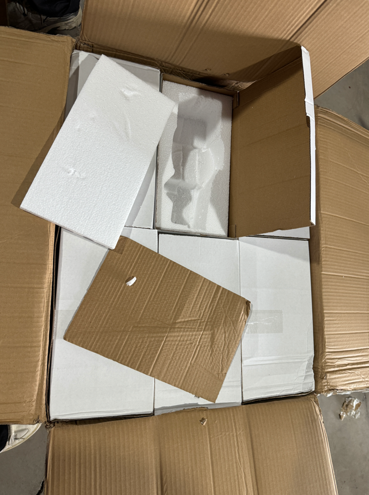 Top-down view of an open export carton containing multiple individually boxed ceramic figurines — each piece secured in its own white inner box with custom foam inserts, showing the bulk wholesale packaging method used by a Yiwu porcelain figurine supplier for safe international freight