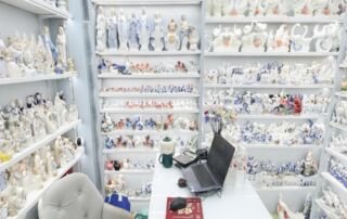Wholesale ceramic and porcelain figurines displayed on floor-to-ceiling shelves at a supplier shop in Yiwu Futian Market District 1 - featuring European lady figurines, swan figurines, angel ornaments, horse figurines, animal sculptures and home decor pieces available for bulk order