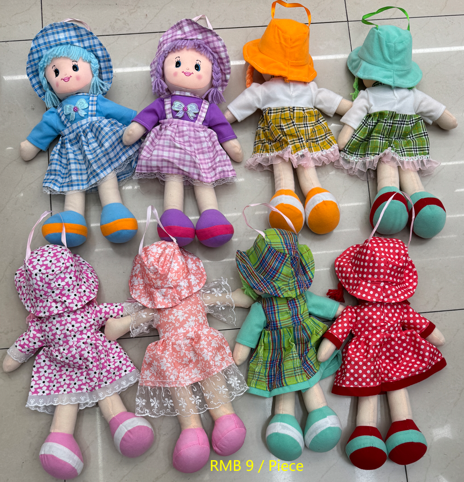 Assorted colorful soft cloth rag dolls with hats and patterned dresses displayed on the floor at Yiwu Toy Market, wholesale price RMB 9 per piece