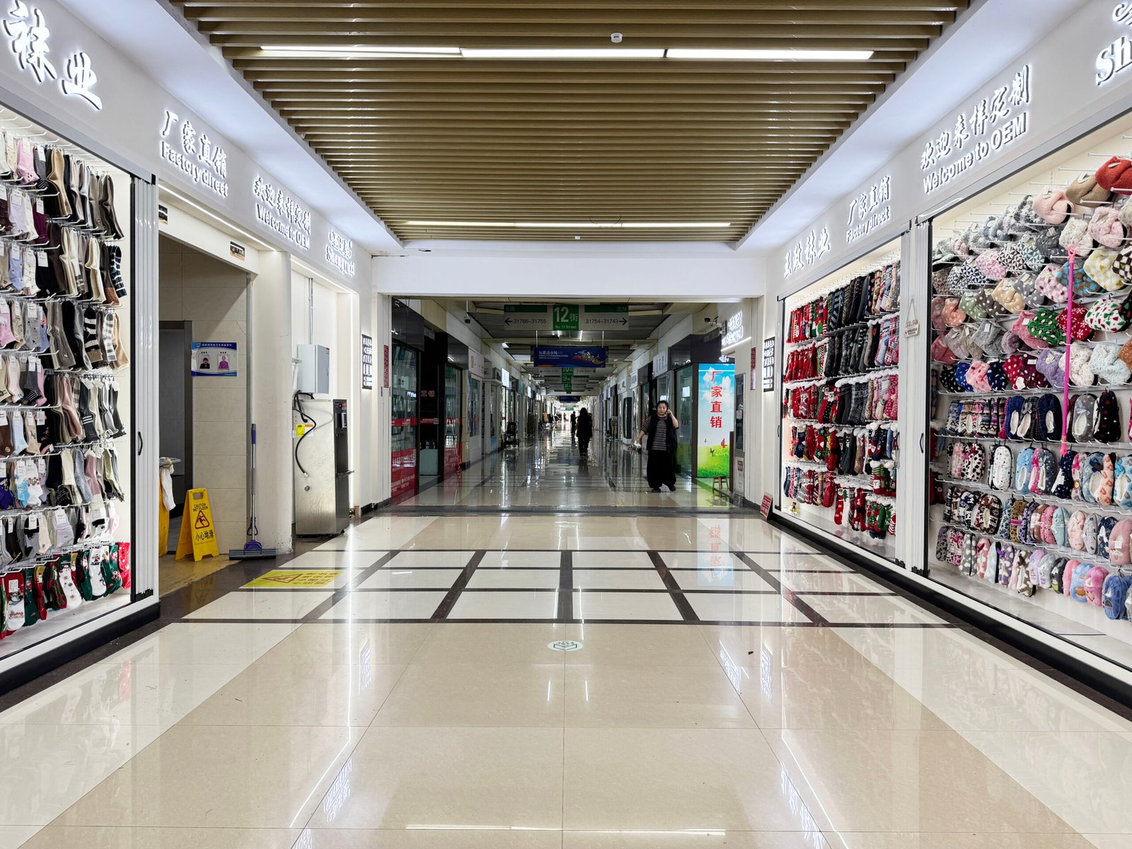 Factory-direct sock supplier stores along a wholesale market corridor in Yiwu, China